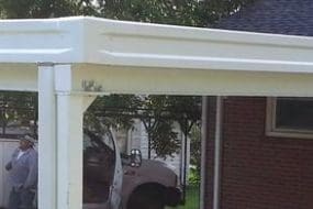 A white carport in the backyard of a house.