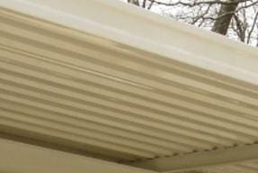 A white metal roof on a house in the woods.