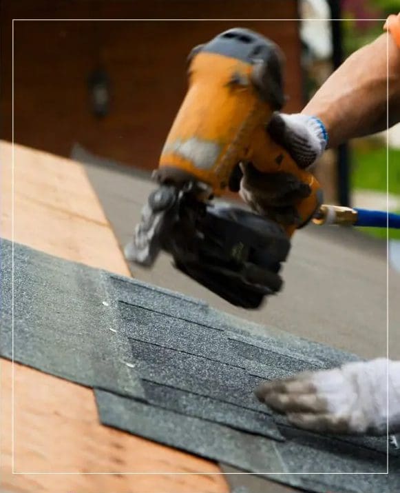 A man is using a sander to install a shingle on a roof.