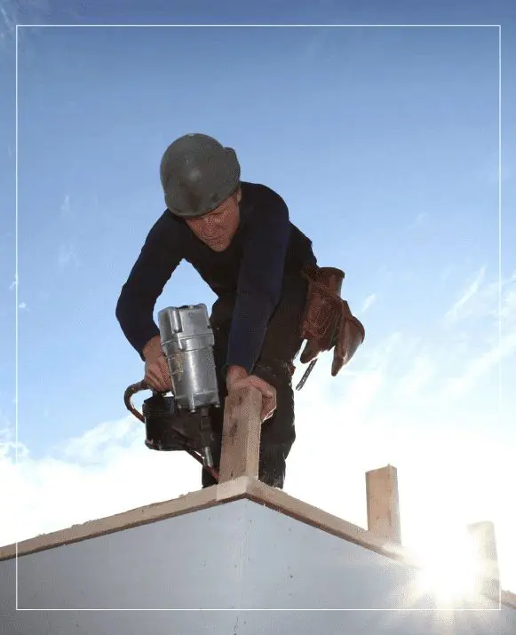 A man is working on a roof with a drill.